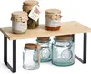 A bamboo shelf with black metal legs holding jars of food products. Produktbild-Vorschau