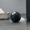 A black soap dispenser with a silver nozzle sits on a countertop next to a bowl of garlic and some foam. Produktbild-Vorschau