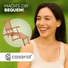 A woman smiling in front of a green background, with a wooden lounge chair and the Casaria logo. Produktbild-Vorschau