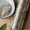 A close-up overhead shot of a bowl of seasoning and a glass jar filled with seasoning, placed on a wooden surface. Produktbild-Vorschau