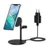 A black 3-in-1 wireless charging stand with a smartphone, AirPods Pro, and an Apple Watch charger, connected to a black power adapter. Produktbild-Vorschau