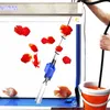 A person is using a gravel vacuum cleaner to clean an aquarium with red fish. Náhled obrázku produktu