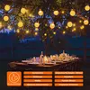 Outdoor dining table set up at dusk with string lights overhead. Voir les images du produit
