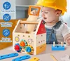 A baby wearing a yellow hard hat and denim overalls plays with a wooden toolbox and tools. Produktbild-Vorschau