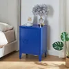 A blue metal nightstand next to a bed, with a lamp and a framed picture on top. Podgląd zdjęcia produktu