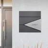 A modern mailbox mounted on a textured wall next to a door. Produktbild-Vorschau