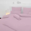 A neatly made bed with pink bedding, including pillows and a bolster pillow. Produktbild-Vorschau