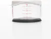 A close-up view of the bottom portion of a clear measuring cup with red measurement markings. Produktbild-Vorschau