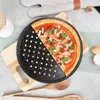 A pizza on a perforated pizza pan, placed on a wooden board, with kitchen utensils and eggshells nearby. Náhľad obrázku produktu