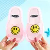 Paar pinke durchsichtige Gummi-Rutschen mit gelben Smileys, von Händen gehalten vor hellblauem Hintergrund Náhled obrázku produktu