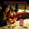 A woman is using her phone at a table with a cup of tea and a Bluetooth speaker. Produktbild-Vorschau