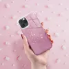 A hand holding a pink glitter phone case against a pink background with marshmallows. Produktbild-Vorschau