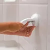 A person's hands are shown attaching a white suction cup grab bar to a tiled wall in a bathroom. Náhled obrázku produktu