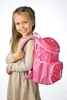 A young girl wearing a beige dress is posing with a pink backpack on her shoulder. Anteprima dell’immagine prodotto