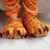 A close-up view of a person's feet wearing tiger paw slippers. Náhled obrázku produktu