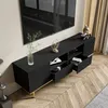 A modern black TV stand with gold accents is shown in a living room setting, with a large TV mounted above it. Produktbild-Vorschau