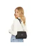 A woman wearing a white turtleneck and blue jeans, posing with a black crossbody bag. Produktbild-Vorschau