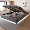 A bed with its storage compartment open, revealing neatly folded linens and blankets. The bed is in a bedroom setting with a window and a rug. Náhled obrázku produktu