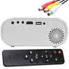 A white mini projector with various ports and a black remote control, along with RCA cables, is displayed against a white background. Voir les images du produit