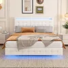 A white upholstered bed with a tufted headboard and footboard, featuring blue LED lighting under the bed and around the headboard. The bed is made up with pillows and blankets, and is set in a bedroom with nightstands and artwork on the wall. Produktbild-Vorschau