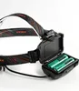 A close-up view of a black headlamp with an open battery compartment showing two green batteries. Podgląd zdjęcia produktu