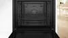 An open oven with a view of the interior and racks, set against a white background with a hint of a room in the background. Produktbild-Vorschau