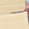 Hellbraune Holzkern-Schaumstoffplatte wird mit roter Schere geschnitten Voir les images du produit