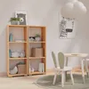 A child's room with a wooden bookshelf, a small table and chair, and wall art. Produktbild-Vorschau