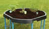 A black mud kitchen with blue legs is filled with soil and small plants, set on a green lawn. Produktbild-Vorschau