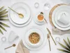 A flat lay of white dinnerware and cutlery, with some greenery and a bowl of granola. Produktbild-Vorschau