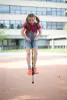 A young girl is jumping on a pogo stick in front of a building. Produktbild-Vorschau