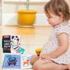 A baby girl is sitting on the floor, looking at a soft baby book. Anteprima dell’immagine prodotto