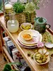 A rustic display of citrus fruits, jam, and a juicer on a wooden shelf. Produktbild-Vorschau