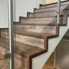 A close-up view of a modern staircase with wooden-look treads and glass railings. Anteprima dell’immagine prodotto