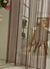 A room interior with a string curtain in the foreground, a window with a plant, and a chair with a painting in the background. Produktbild-Vorschau