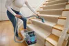 A person is cleaning a carpeted staircase with a portable carpet cleaner. Podgląd zdjęcia produktu