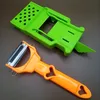 A green vegetable slicer and an orange peeler are placed on a brown surface. Voir les images du produit