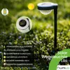 A solar garden light in a grassy area with flowers. Náhľad obrázku produktu