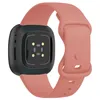 The back of a pink Fitbit Versa 4 smartwatch band with the watch body attached. Produktbild-Vorschau
