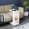 A white side table with books and a cup of coffee is placed next to a beige sofa in a living room setting. Náhľad obrázku produktu