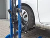A close-up view of a blue car jack lifting a white car. Produktbild-Vorschau