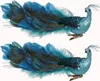 Two decorative clip-on peacock ornaments with blue and teal feathers and glittery bodies, displayed against a white background. Produktbild-Vorschau