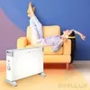 A woman relaxes on a chair with her legs up, listening to music, while a portable electric heater is in the foreground. Produktbild-Vorschau
