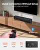 A soundbar is placed on a wooden TV stand in front of a large TV. A hand is holding a remote control, and icons for HDMI, AUX, and USB are displayed at the bottom. Produktbild-Vorschau