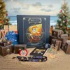 A collection of One Piece themed merchandise, including an advent calendar, is displayed on a sandy beach with Christmas trees in the background. Produktbild-Vorschau