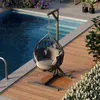 A hanging chair next to a swimming pool on a wooden deck. Podgląd zdjęcia produktu