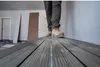 A person wearing work boots and pants walks on a plank in what appears to be a construction or renovation site. Produktbild-Vorschau