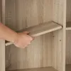 A hand is inserting a shelf into a wooden cabinet. Náhled obrázku produktu
