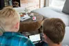 Two children are playing a game on a tablet in a living room. Produktbild-Vorschau