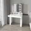A white makeup vanity with a tri-fold mirror and LED lights, placed in a bedroom setting next to a window with curtains. Náhled obrázku produktu